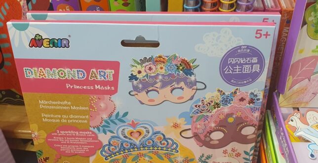 The image shows a brightly colored box with the clear text 'Princess Masks' written in bold font. The box contains kid craft masks designed with princess themes, including crowns, tiaras, and glittery embellishments.