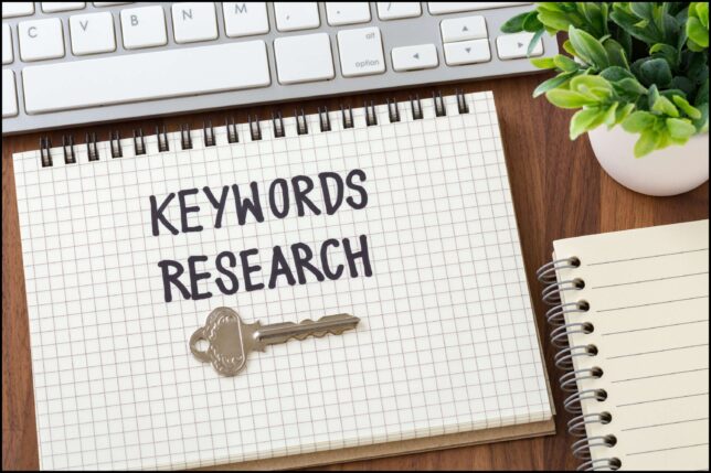 A key on a notebook next to a keyboard representing keyword research for B2B food websites.